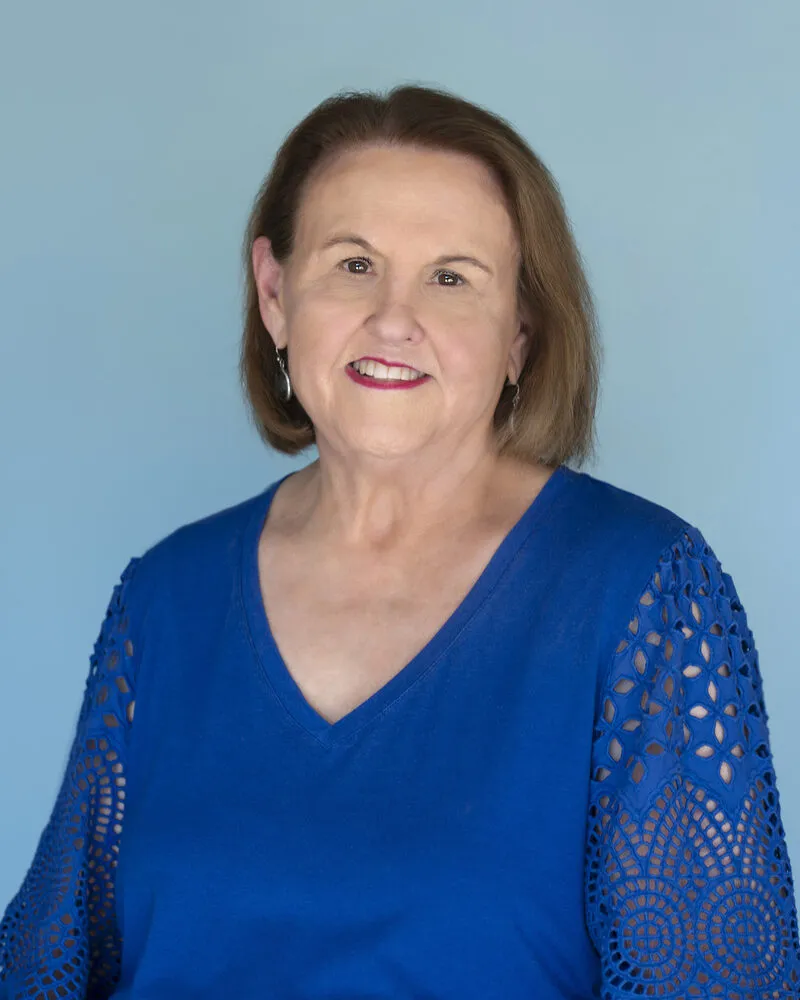 Dr. Jan Martin Dunn, smiling, wearing a royal blue top with eyelet lace sleeves.