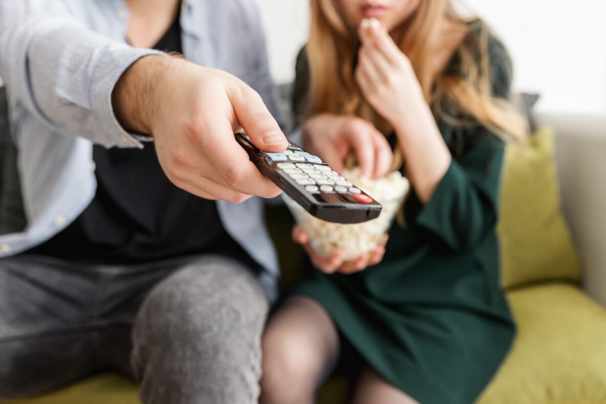 Why We're Drawn to Shows We Hate, According to Psychology Couple-Watching-TV